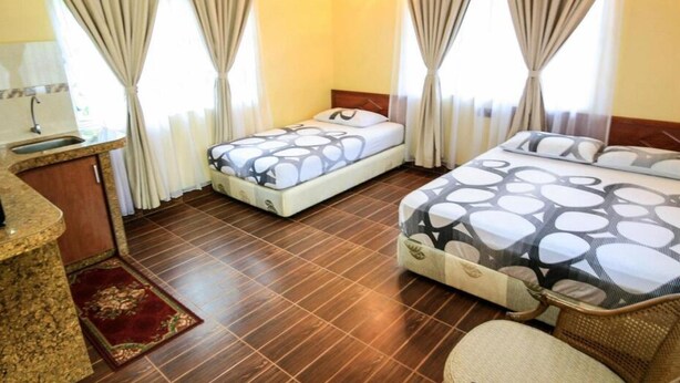 Habitación de hotel con dos camas, un escritorio pequeño con espejo y una alfombra roja.
