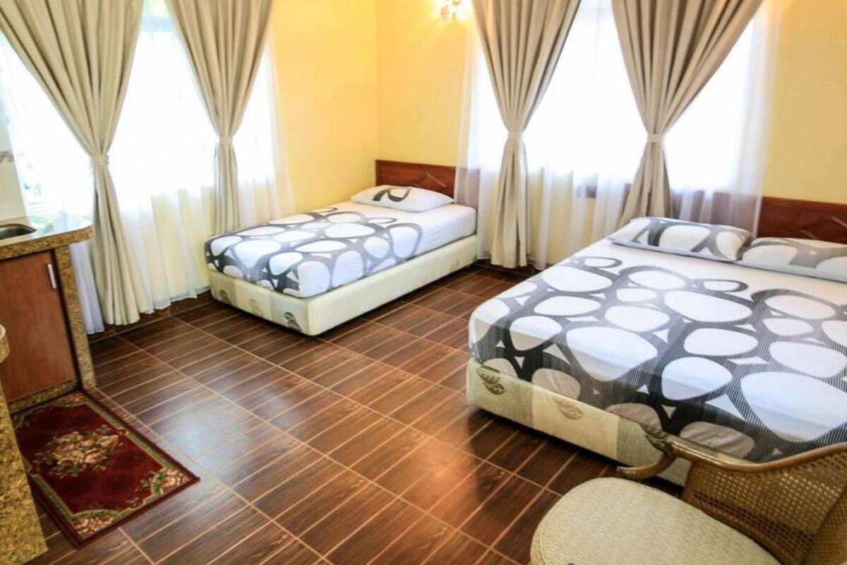 Een hotelkamer met twee bedden, een klein bureau met spiegel, en een rood tapijt.