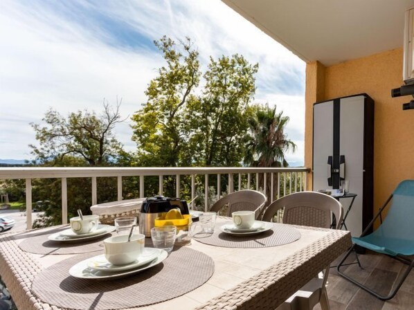 A balcony with a table set for two, outdoor chairs, a bottle of water, and a cup.
