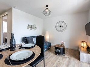 A modern living room with a dining area, featuring a sofa, a coffee table, and a TV.