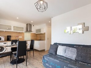 A compact living space with a kitchenette, a dining area, and a sofa with patterned cushions.