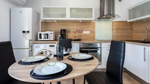 Una cucina moderna con mobili bianchi, un forno a microonde, una macchina da caffè e un piano cottura. C'è un tavolo da pranzo con piatti e bicchieri.