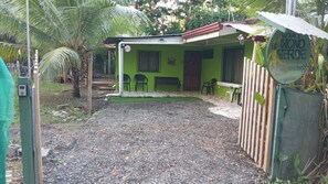 Une maison verte avec un patio, une clôture en bois et une enseigne sur laquelle on peut lire « MONO VERDE ».