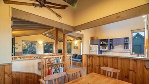 Ein gemütliches Blockhaushaus-Interieur mit einer Essgegend aus Holz, einer Küche mit integrierten Geräten und einem großen Fenster, das natürliches Licht hereinlässt.