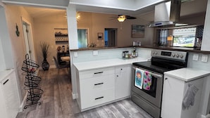 A modern kitchen with white cabinetry, a stainless steel oven, and a built-in microwave. - New Listing!! Gulf Coast beaches, 14 min to ManasotaKey, private heated pool! (Englewood)