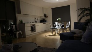 Una cucina moderna con mobili bianchi, un'area pranzo con sedie bianche e un divano dai colori scuri.