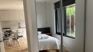 Una camera da letto moderna con un letto grande, un comodino e una finestra vista verde.