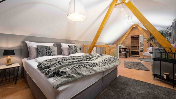 Un dormitorio con una cama grande, una mesita de noche, una lámpara y una viga de techo de madera.