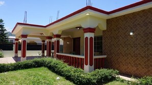 Un edificio moderno con un porche cubierto, una fachada de paredes de cerámica y un césped cuidado.