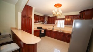 Una cocina con armarios de madera, un refrigerador de acero inoxidable, una encimera y una araña.