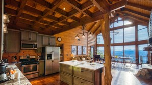 Una cocina amplia con vigas de madera, una isla grande y vistas a las montañas a través de amplias ventanas.