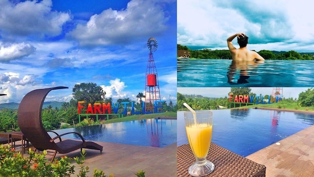 A pool area with a sign reading "FARM VILLE," a windmill, and a glass of orange juice on a table. - Taal Maranan Farmville Inc. (Taal)