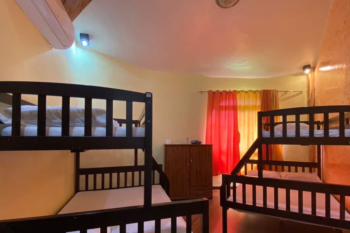 A room with bunk beds, a wooden cabinet, and a window with curtains.