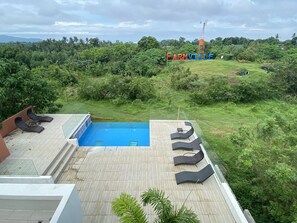 A rooftop pool area with lounge chairs and a view of the surrounding landscape. - Taal Maranan Farmville Inc. (Taal)
