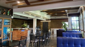 A modern restaurant with a wooden ceiling, black tables, and blue seating. - Taal Maranan Farmville Inc. (Taal)