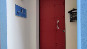 En rødmalede dør med et brevindsug, en blå skiltplade og et skilt med nummer 812 på væggen.