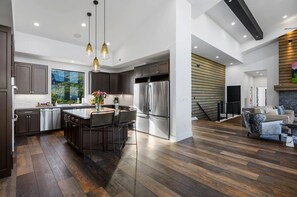 Een moderne keuken met donker houten vloeren, roestvrijstalen apparatuur en een centraal kookeiland met barstoelen.