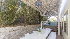 A covered patio with a long white table, chairs, and potted plants. - Year Round Heated Pool, Hot Tub, Pet Friendly (Las Cruces)