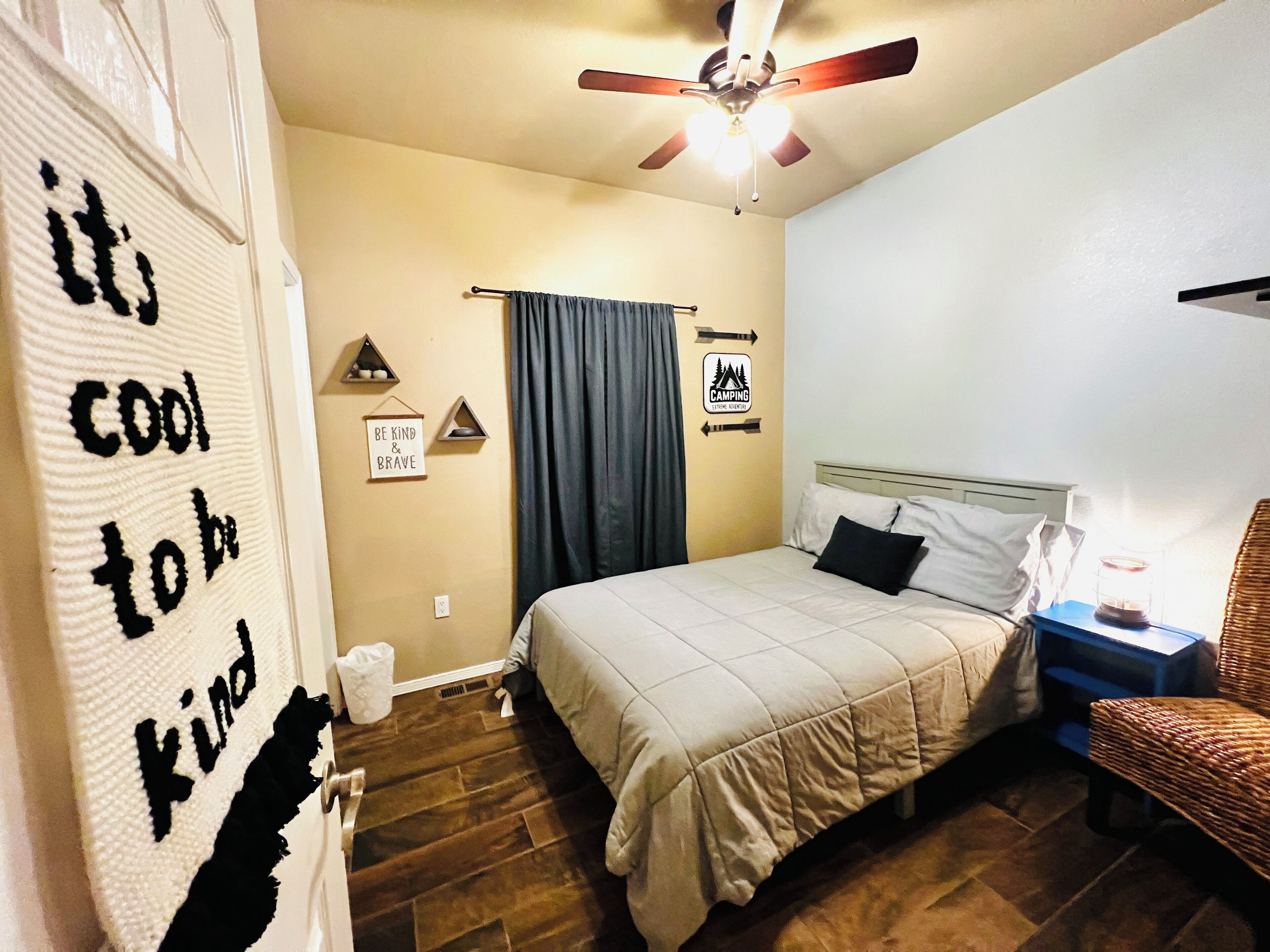 Une chambre à coucher avec un lit, un ventilateur de plafond, une table de chevet et une chaise.
