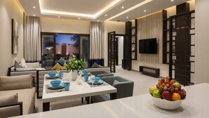 A modern living room with a dining area, a TV, and a large window with curtains. - Dorat Najd Resort (Diryah)