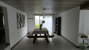 Ein geräumiges Zimmer mit einem Holztisch, einer Vase mit Blumen und Blick durch ein Fenster.