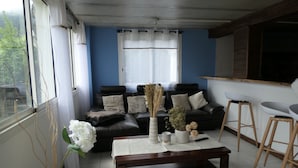 Ein Wohnzimmer mit einem dunkelbraunen Ledersofa, einem Holztisch und einer Blumenvase.
