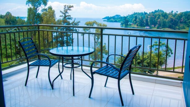 Een balkon met een ronde tafel en twee stoelen, met uitzicht op water en groen.
