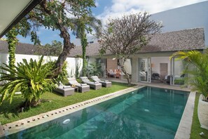 A private pool area with lounge chairs, a small garden, and a glass-enclosed patio. - Villa Mia by Villa Finder (Canggu)