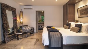 Un dormitorio moderno con una cama grande, una silla, una mesita y un espejo.