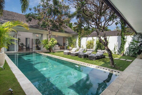 A modern house with a swimming pool, outdoor seating, and lush greenery. - Villa Mia by Villa Finder (Canggu)