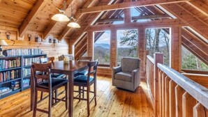A wooden interior with a dining area, bookshelves, and a view of the outdoors.