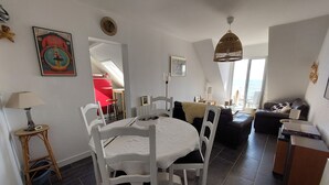 A dining area with a round table and chairs, a red accent wall, a large window, and a view of the sea. - Wild coastline, exceptional sea view, close to shops and TGV station (Le Croisic)