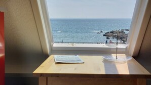 A window view of the ocean with a wooden table and a newspaper. - Wild coastline, exceptional sea view, close to shops and TGV station (Le Croisic)