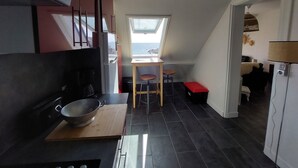 A compact kitchen with a view of the sea, a small dining area, and a red bench. - Wild coastline, exceptional sea view, close to shops and TGV station (Le Croisic)