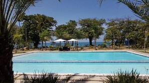 Relax by the oceanfront pool surrounded by lush greenery and palm trees.