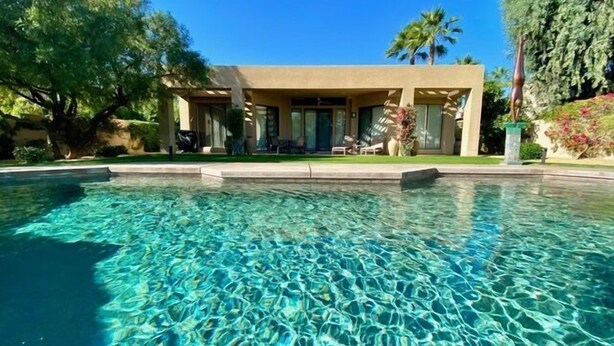 Une piscine aux eaux cristallines, avec une maison moderne en arrière-plan.
