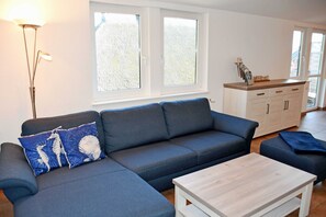 Ein modernes Wohnzimmer mit einem grauen Ecksofa, einem Holztisch und einem weißen Schrank.