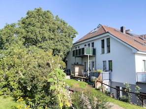 Ein zweistöckiges Haus mit Balkon, Garten und kleiner Terrasse.