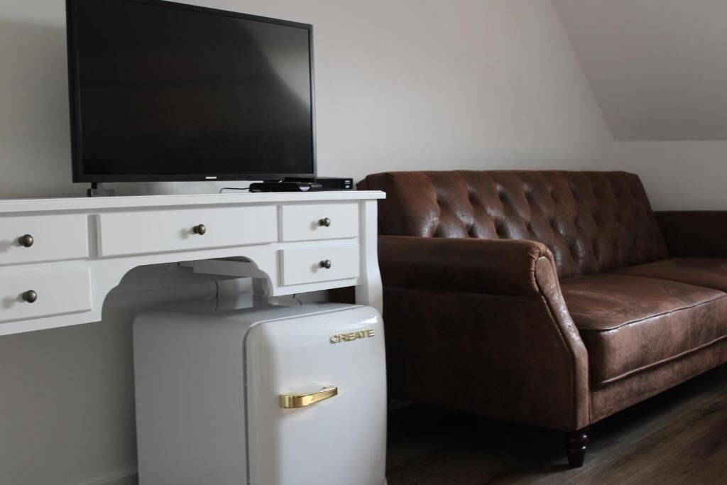 Un salon équipé d’un téléviseur à écran plat, d’un mini-réfrigérateur blanc et d’un canapé en cuir marron.