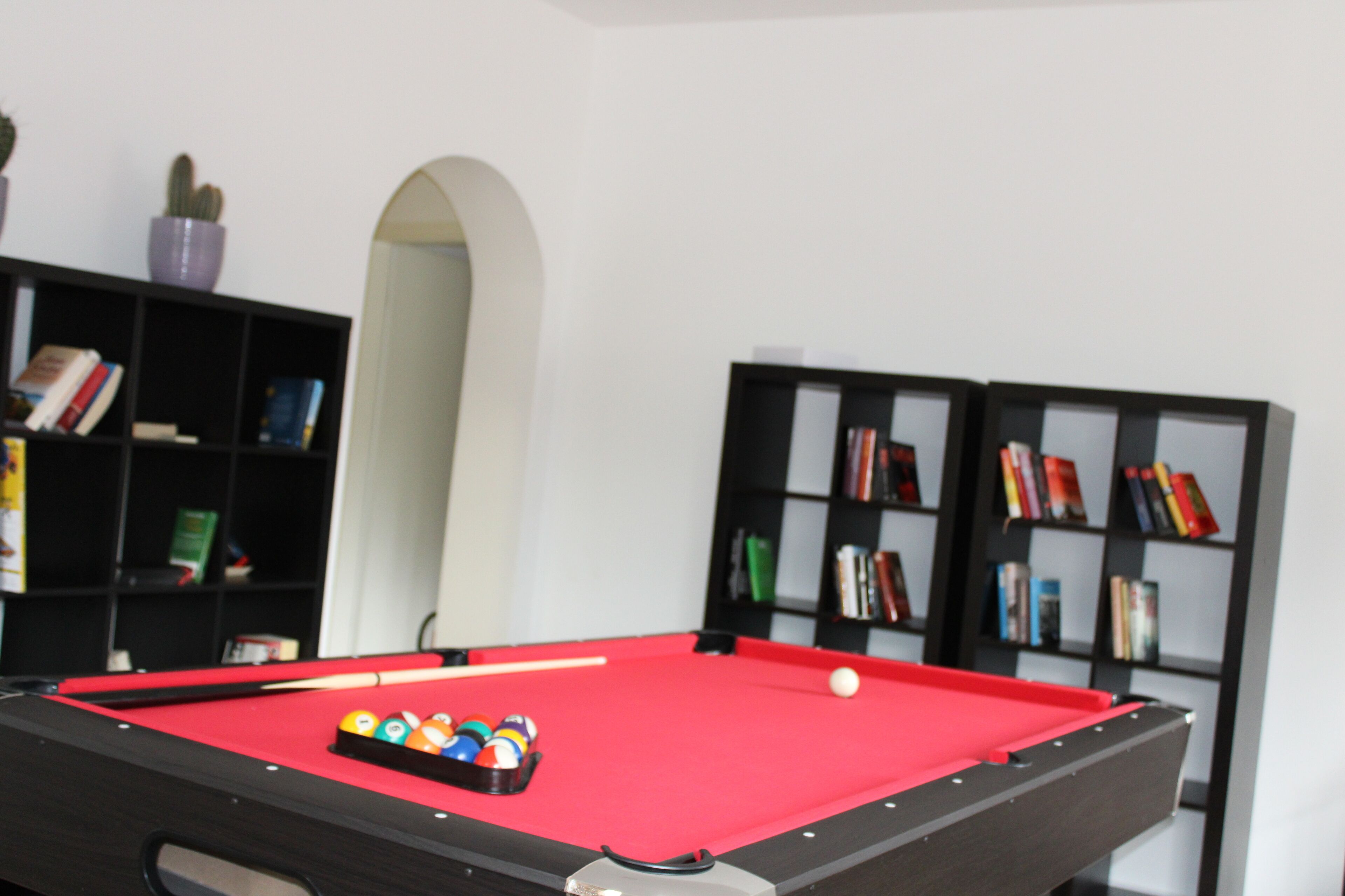 Une table de billard avec des billes, entourée d’étagères à livres.