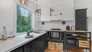 Una cocina moderna con un amplio ventanal, armarios blancos y horno empotrado.