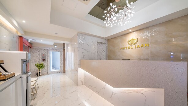 A modern hotel reception area with a marble floor, a coffee machine, and a reception desk with the hotel name. - Indeokwon Ian Hotel (Anyang)