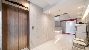 A modern interior with a wooden door, marble walls, a kitchen area with a refrigerator, and a seating area with chairs. - Indeokwon Ian Hotel (Anyang)