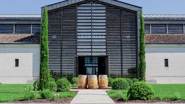 A modern building with a sloped roof, large windows, and three wooden barrels in front. - Le Pavillon - The Lion (Néac)