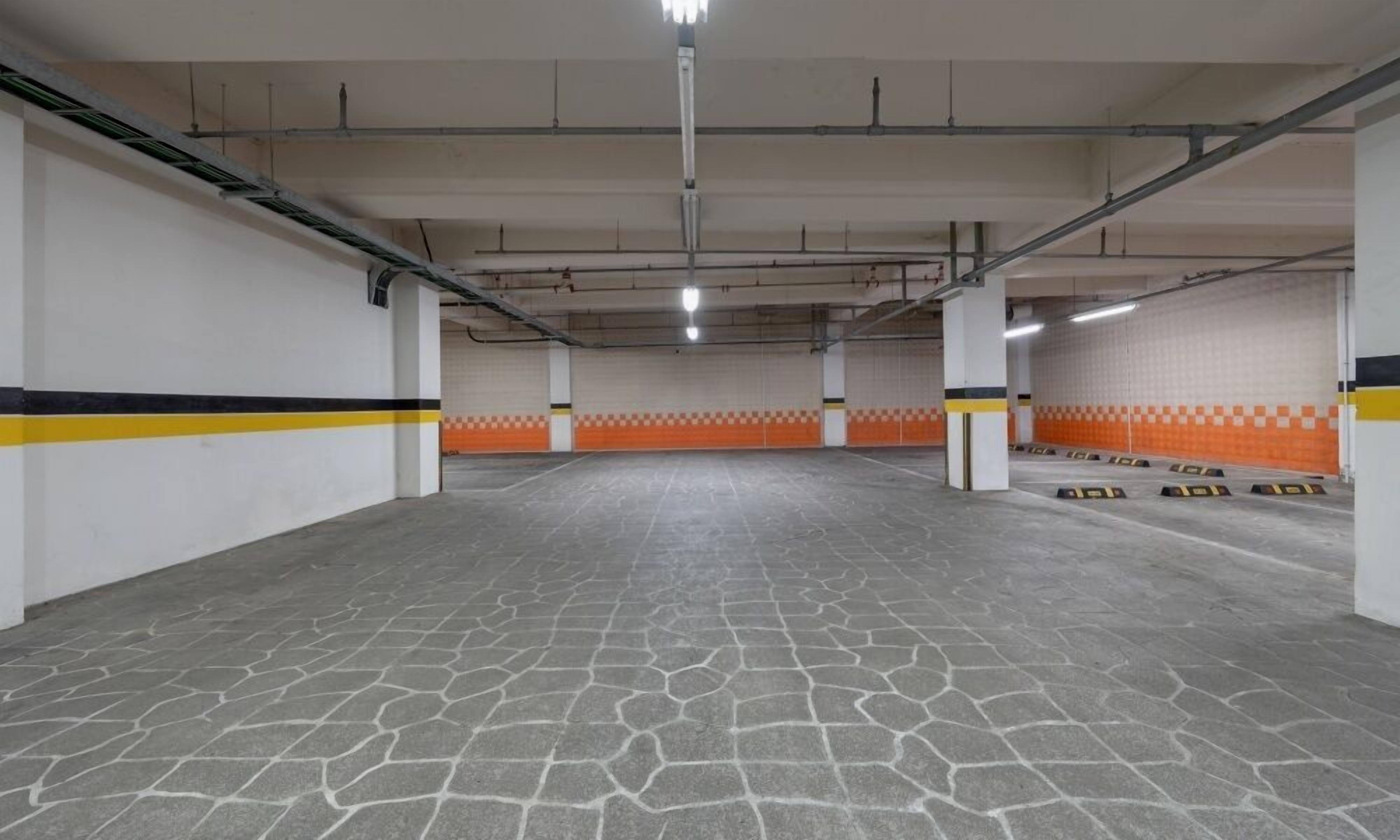 An empty parking garage with a tiled floor and orange and white checkered walls.