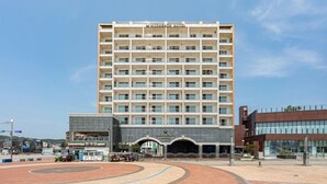 A multi-story hotel with a central entrance and a parking area in front. - Daecheon Mud Beach Hotel (Boryeong)