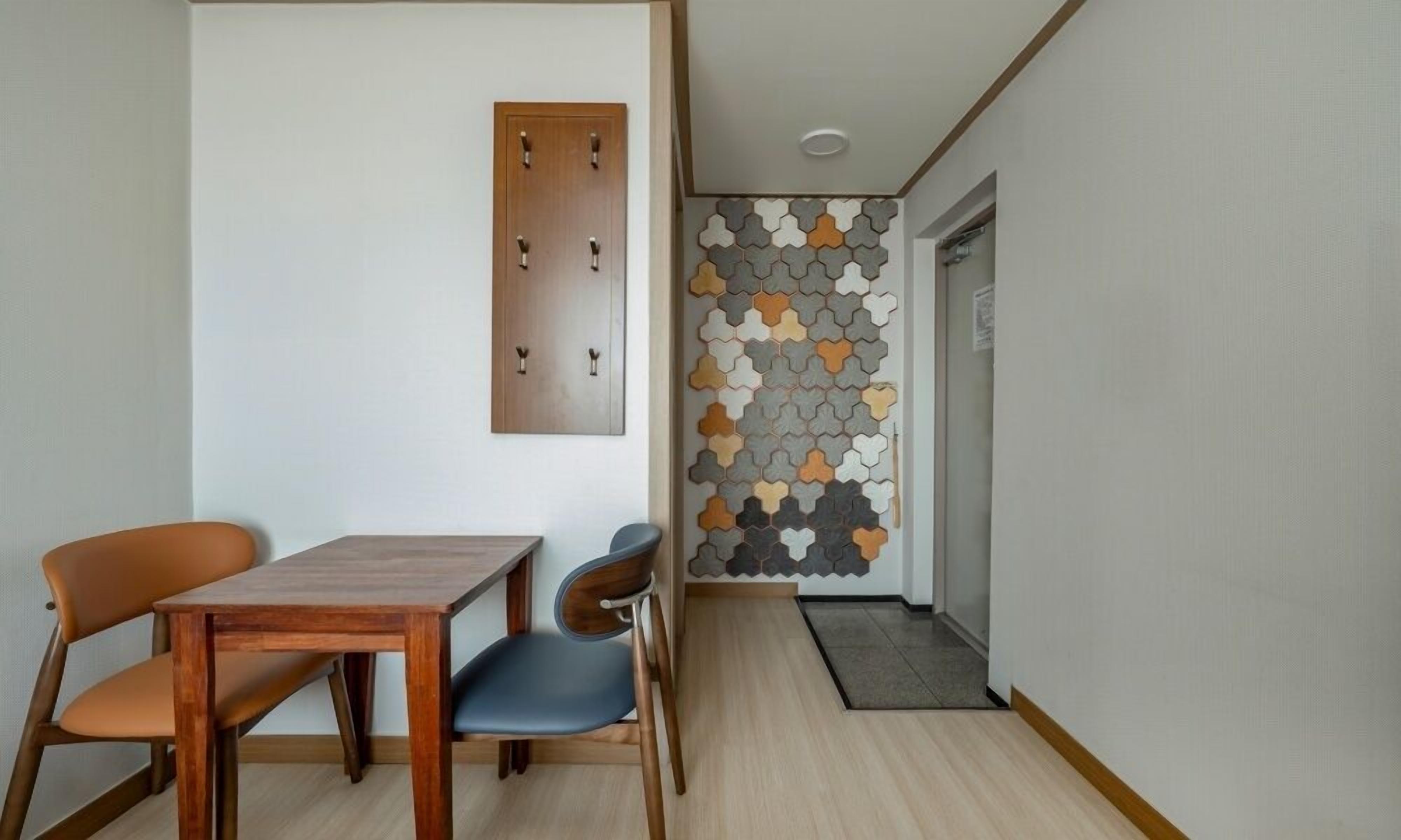 A hallway with a wooden door, a wall-mounted light fixture, and a patterned wall.