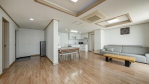 A spacious living area with a dining table, a sofa, and a kitchen in the background. - Daecheon Mud Beach Hotel (Boryeong)