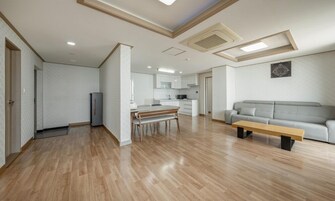 A spacious living area with a dining table, a sofa, and a kitchen in the background.