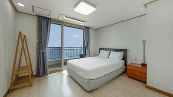Une chambre d’hôtel avec un lit, une échelle en bois, une table de chevet et une vue sur la mer par une grande fenêtre.